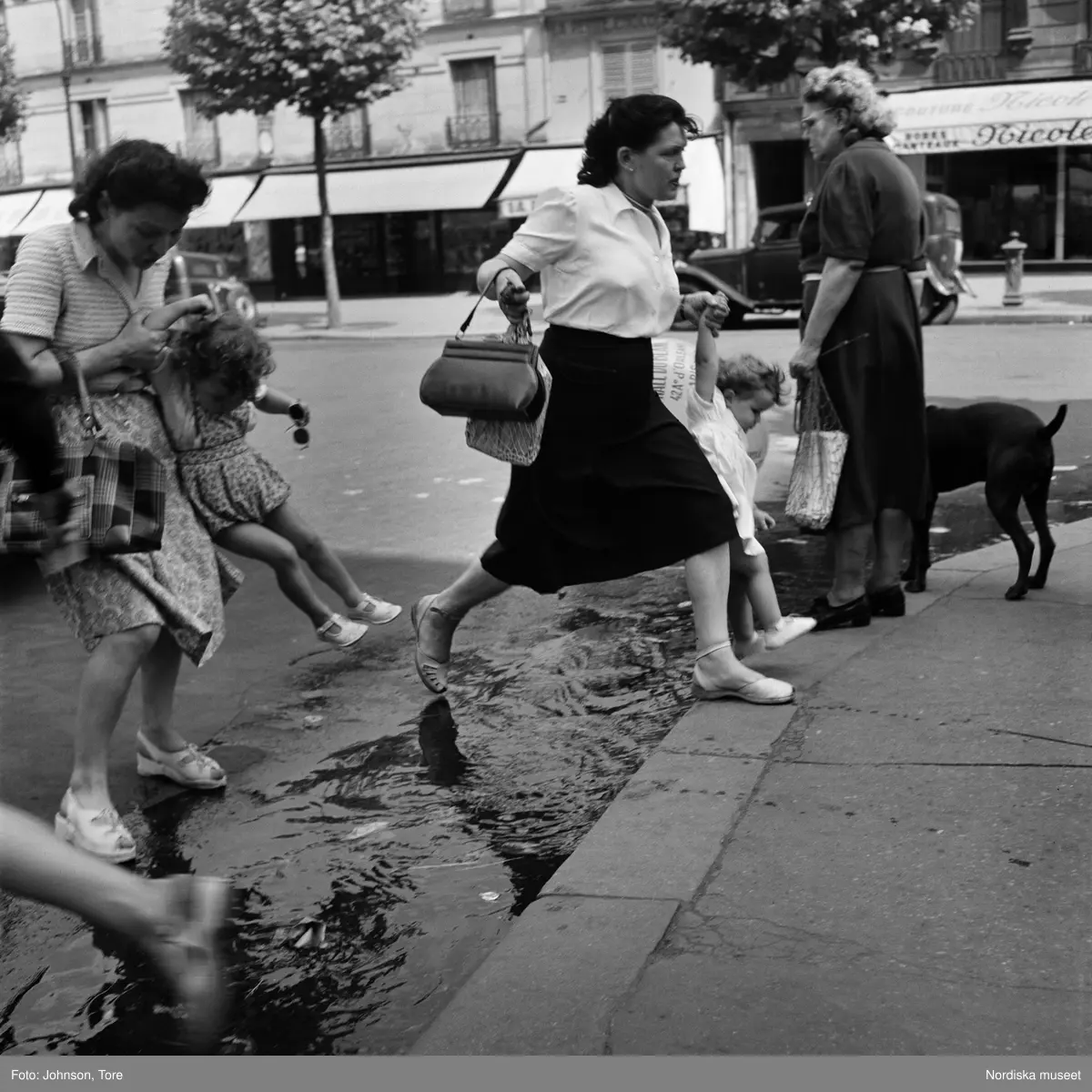 Paris. Fotgängare hoppar över vattenpöl vid övergångsställ.