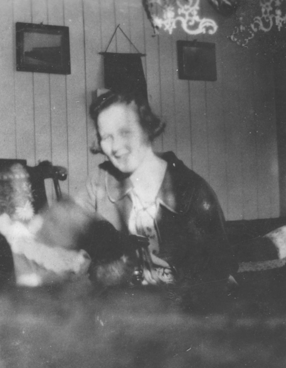 En ung dame, Signe, sitter i en stue med et barn liggende på sofaen.