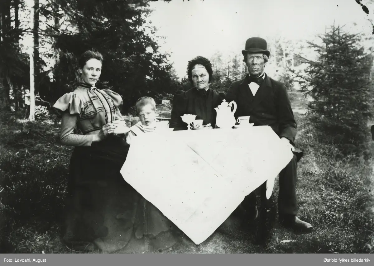 Engebret Hansen og Nikoline Abrahamsdatter Haugane, fra Haugane i Ullerøy, Skjeberg med datter og hennes sønn, 1898. Husmannsplass under gården Lileng østre. De hadde fire barn: Johan, Hans, Hanna og Elen. Hanna ble født 1862 og Elen i 1867. Det kan være Lene eller Hanna som er på bildet, og hennes sønn.
Det var flere brn i familien. 
Det vises også et utsnitt av bildet. 

Ifølge folketelling 1891 for Skjeberg drev Engebret : "Skrædderhåndværk for egen Regning og Pladsbrug som Husmand".