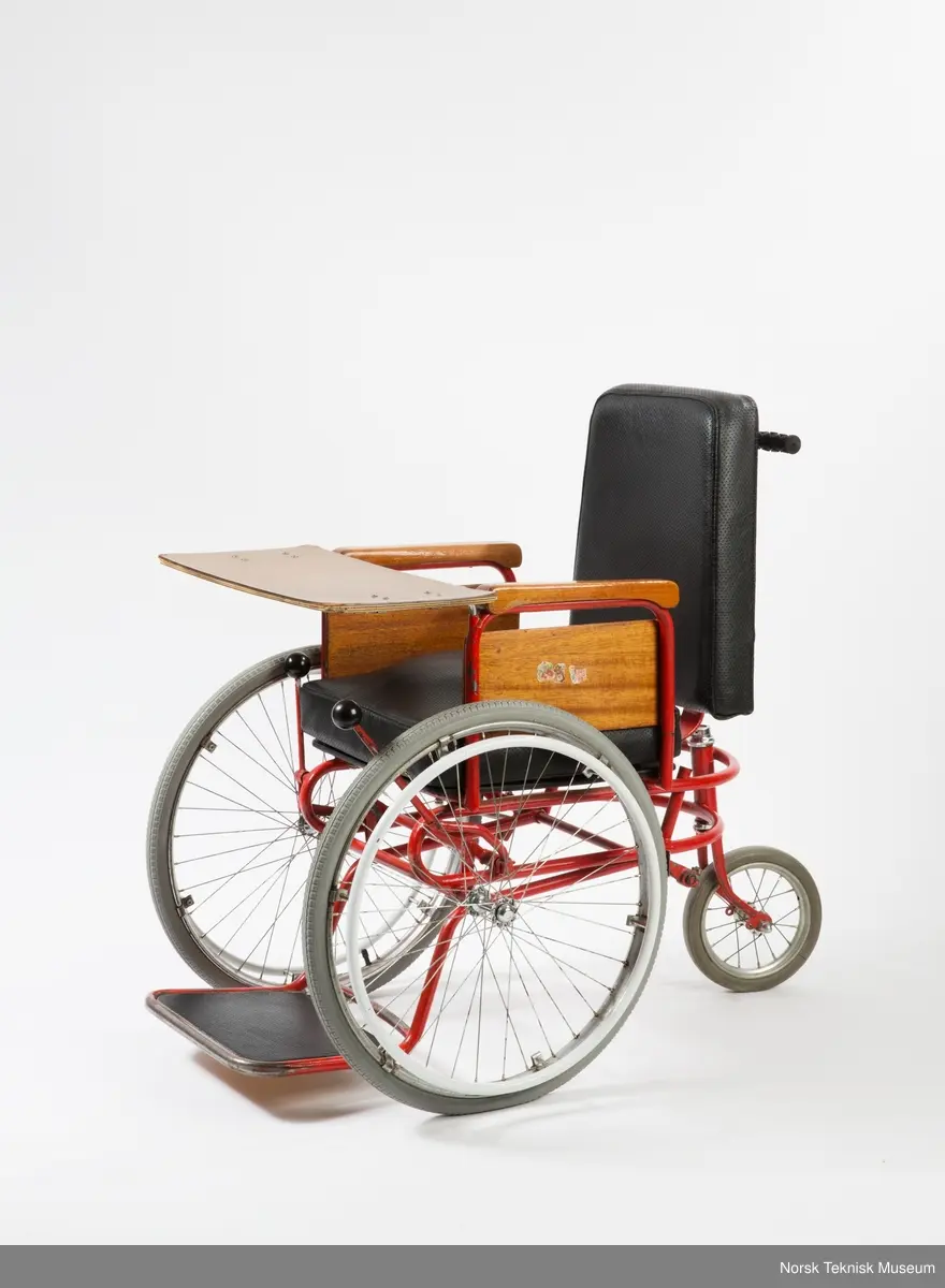 Rullestolen er i metall og mørkt tre, og stilen er funkis.
Terje har malt metallet rødt (opprinnelig farge kan ses bak, ved skruefestet) og pusset og lakket armlenene, ellers er den original.