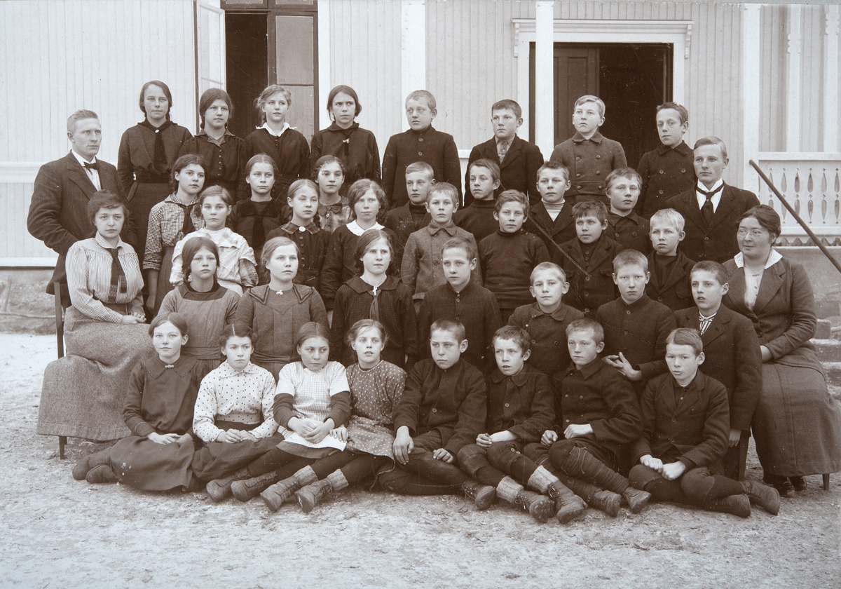 Skolebilde Brovold skole. (Kan dette være 7. og 6. klasse i storskola? 12-14 år gamle) De samme fire lærere, og samme opptakssituasjon som for 0415-03666. Ludvig Zimmermann (lærer Brovold 1911-51, f. 1890), Agnes Bjerke (f.1885, lærer Brovold 1910-1921), Sigvald Holen (lærer Brovold 1914-1920, fra Vegårdshei, f.1893?, senere rektor i Bergen). Agnes Hommelstad (ambulerende husstellærer i Folkeskolen,1916-1919, f.1891, elev på Dystingbo i 1910).
Elevene, Ester Skogen (f.1902) er på bildet, bakerste rad, først fra venstre.