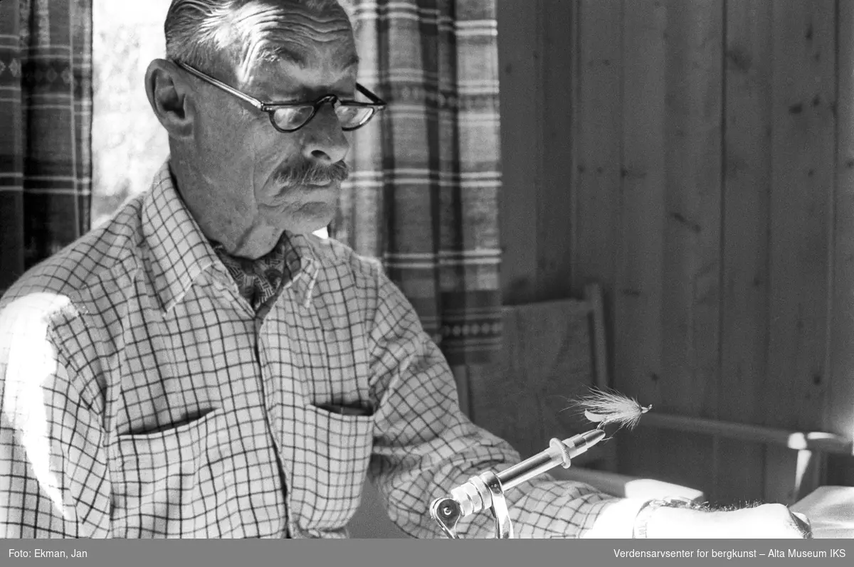 Fluebinding i hytteinteriør.

Fotografert mellom 1970 og 1988.

Fotoserie: Laksefiske i Altaelva i perioden 1970-1988 (av Jan Ekman).
