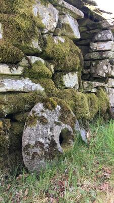 mosegrodd mur med rund stein ved sidan av