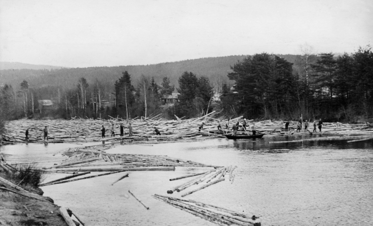 Tømmerhaug ved Stormo lense i Juiråa i Nord-Odal i Hedmark. Fotografiet ble tatt i 1952. Vi ser 20 fløtere med haker i arbeid ved haugens ytterkant. Like ved haugen lå det en robåt som fløterne antakelig brukte når de tok seg til og fra haugen. I 1954 ble det innmeldt 84 884 tømmerstokker til Juråa.