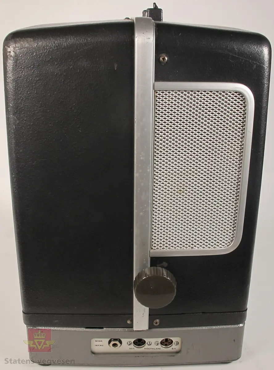 BELL & HOWELL MODEL 642. 16 mm filmfremviser i mørk grå koffert av glassfiber, med defekt bærehåndtak. Den ene delen av kofferten har høyttaler av merket Goodmans, ledning for tilkobling av høyttaler og to klistremerker med påskrifter. Filmfreviseren har eget panel for justering av lyden. Bak på kofferten er det to skiltplater med innskrifter, MODEL 642 SK SERIAL No. K418 220V-1100 W - 50 ~ MADE IN ENGLAND og HANS H. KNUTSEN & CO. OSLO TYPE 642 No 418 P.VOLT 200/250 50 ~ S.VOLT AMP. 1200W. Veske, strømledning, ekstra lyspære og to tomme filmruller følger med filmfremviseren.