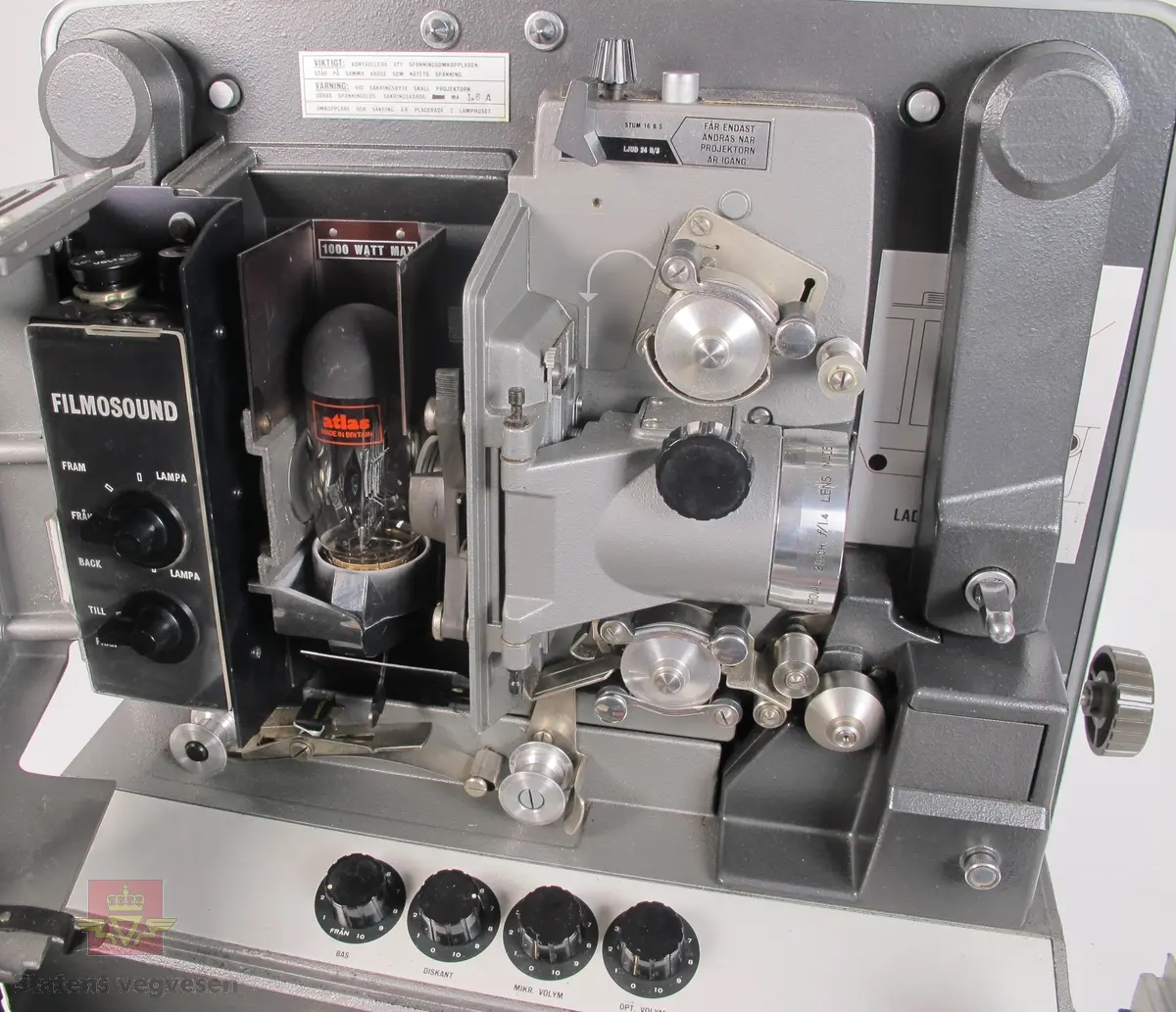 BELL & HOWELL MODEL 642. 16 mm filmfremviser i mørk grå koffert av glassfiber, med defekt bærehåndtak. Den ene delen av kofferten har høyttaler av merket Goodmans, ledning for tilkobling av høyttaler og to klistremerker med påskrifter. Filmfreviseren har eget panel for justering av lyden. Bak på kofferten er det to skiltplater med innskrifter, MODEL 642 SK SERIAL No. K418 220V-1100 W - 50 ~ MADE IN ENGLAND og HANS H. KNUTSEN & CO. OSLO TYPE 642 No 418 P.VOLT 200/250 50 ~ S.VOLT AMP. 1200W. Veske, strømledning, ekstra lyspære og to tomme filmruller følger med filmfremviseren.