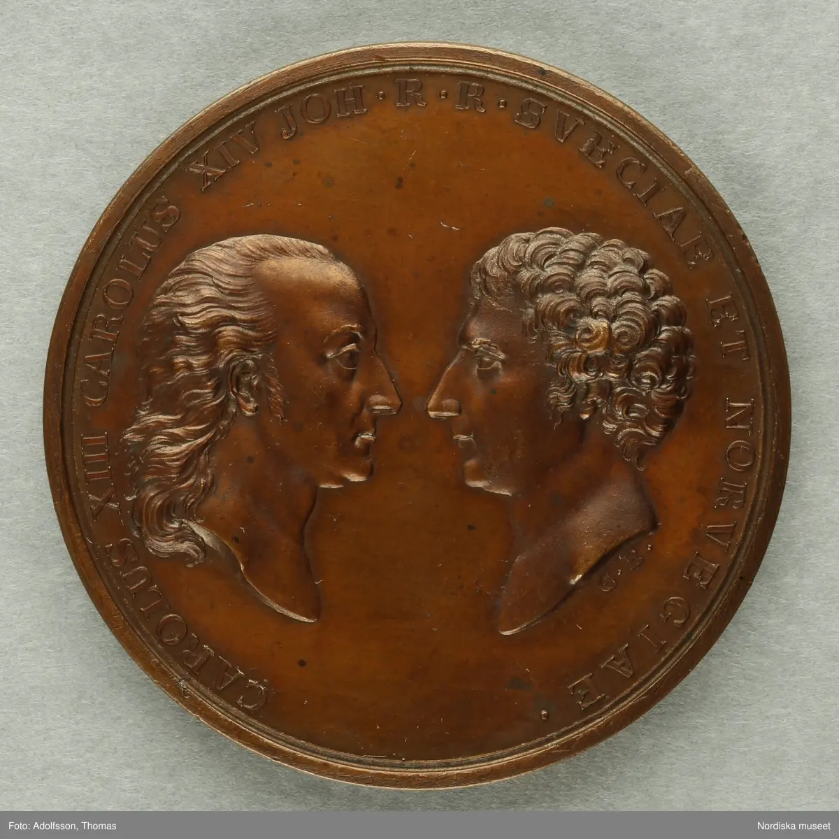 Huvudliggaren.
"2 minnespenningar.
a) I brons. Karl XIV Johan uppstigen på Sveriges och Noriges troner 5/5 1818. Åtsidan Carl XIII och Carl XIV Johans bröstbilder vända mot hvarandra, jmfr. Hildebrand, B. E. 'Sveriges och svenska konungahusets minnespenningar, praktmynt och belöningsmedaljer' del 2, sid 335, nr 22.
b) I brons. Kronprins Oscars förmälning med prinsessan Josefine af Leuchtenberg, i Stockholm den 19 juni 1823. Åtsidan: kronprinsens och kronprinsessans brösbilder förenade. Jmfr. Hildebrand, B. E. 'Sveriges och svenska konungahusets minnespenningar, praktmynt och belöningsmedaljer' del 2, sid 405 nr 7.
G. löjtnant C. V. E. Ridderstad 13/12 1876."