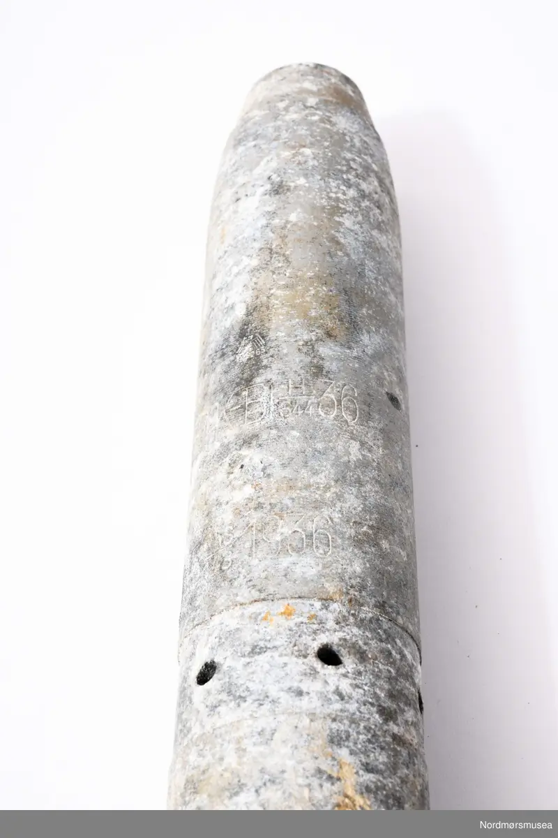 Tysk brannbombe sluppet fra tyske fly (sannsynligvis Heinkel 111 flystasjonert på Værnes) fra aprildagene i Kristiansund 1940. En av de få som ikke virket. Bakerste del mangler. Sylindirsk med flat bunn og topp. Avsmalnende felt bak for feste av framstykke. I motsatt ende er det 6 hull og to mindre lenger ned. Se foto KMb-1987-005.1963