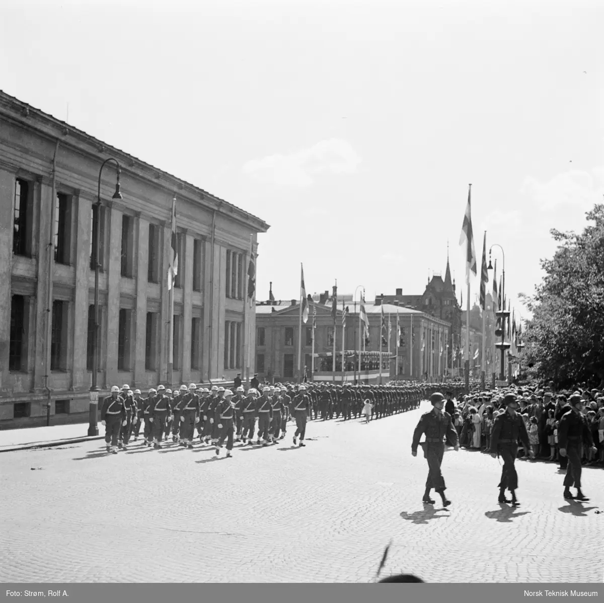 Opptog, USAs nasjonaldag, marsjerende soldater passerer tilskuere ved Universitetet i Oslo, Liten jente løper med blomster mot soldatene. 4. juli 1945.