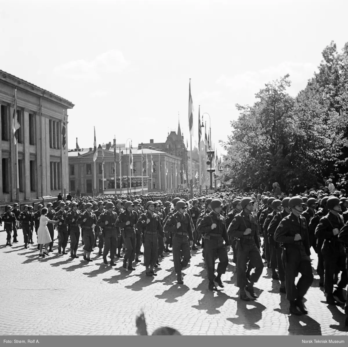 Opptog, USAs nasjonaldag, marsjerende soldater passerer tilskuere ved Universitetet i Oslo, Ung kvinne gir blomster til soldat. 4. juli 1945.