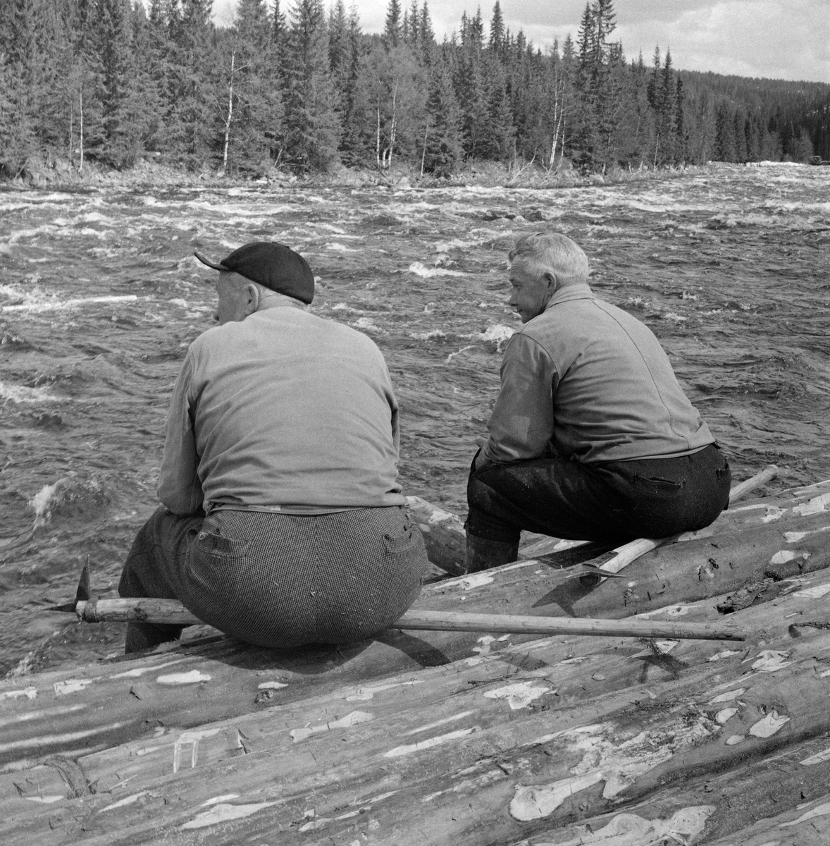 To arbeidskledde tømmerfløtere, fotografert mens de kvilte på ei tømmervelte ved Åstholmen i Vang allmenning. Fotografiet er tatt under utislagsarbeid våren 1969. Åstavassdraget har sine kilder i de østlige fjelltraktene i Øyer (i Oppland fylke). Derfra renner elva sørøstover gjennom de nordre Hedmarksallmenningene før den skjærer østover og renner ut i Glomma i Åmot i Østerdalen. Fotografiet, som er tatt i mai måned. I løpet av foregående vinter var tømmer fra driftene i allmenningsskogen kjørt fram til vassdraget og lagt  i strøvelter. I slike velter lå stokkene lagvis, med tettlagte floer av tømmer parallelt med strømretningen, og med enkelte strøstokker på tvers mellom hver slik flo. Poenget var at virket skulle få lufting, og dermed noe redusert fuktighetsinnhold og økt flyteevne, før fløtinga.

Åsta var fløtbar i om lag tre mils lengde, men fløtinga på den øverste delen av denne strekningen var usikker.  Dessuten var det slik at allmenningene i Ringsaker, Furnes og Vang tok mye av tømmeret til egne sagbruk.  Derfor var den nedre delen av dette vassdraget - fra Djuposet og nedover - at fløtingsaktiviteten var størst.  I 1969 ble det fløtet snaut 4 000 kubikkmeter tømmer i Åsta.  I prioden 1950-1959 var gjennomsnittlig årlig fløtingskvantum i denne elva 4827 kubikkmeter, så fløtingskvantumet i 1969 var ikke illevarslende lavt.  Dette var likevel nest siste sesong med fløting i dette sidevassdraget.

Utislag fra tømmervelter ved Åstavassdraget. Ved Åstholmen i elva Åsta, Vang, Hedmark. Åstdalen. Åstadalen.