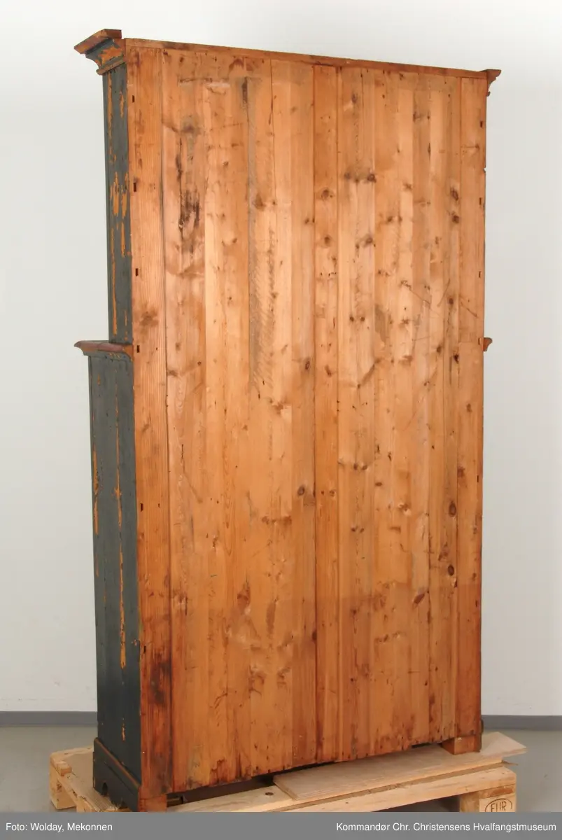 Vanlig form på skap i tiden 1840-60. Overmalt i 1920-årene med ny, naiv dekorasjon - forsøk på kopi av den originale? Original maling bevart under. Skiftet gesimslist og bunnseksjon. (Befaring Jon Brænne, NIKU 23/8-2001)
