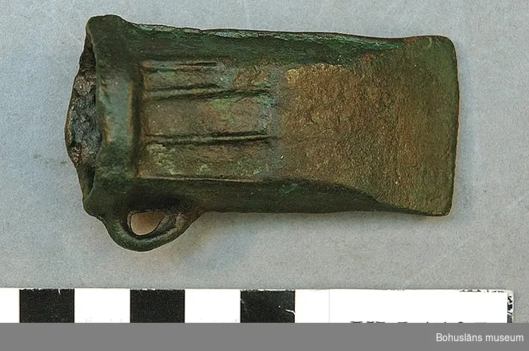 Holkyxa med öra och upphöjda dekorlister, L. 7 cm. Intakt. Yngre bronsålder, period IV. Föremålet ingår i ett depåfynd med sammanlagt 4 bronser (två spjut + två holkyxor) upphittade i Vidingen, Kville socken, Tanums kn. Förvärvat till Uddevalla museum år 1897.

Ur handskrivna katalogen 1957-1958:
Hålcelt. L. 7,0 x Br. 3,9 cm. Holkyxa. Föremålet helt. Av brons. Depåfynd Kville, Bohusl. 1897.  4

Lappkatalog: 1:16

Landskap BOHUSLÄN