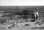 En kvinna och en man står vid staketet på Tabergs topp och tittar på utsikten över Taberg och Skarmaden (Norsgårdsgölen).