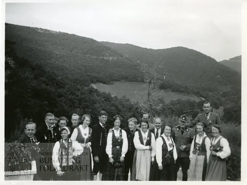 Gruppebilde med menn og kvinner i bunad, samt menn i dress og uniform.