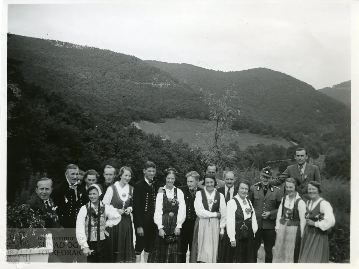 Gruppebilde med menn og kvinner i bunad, samt menn i dress og uniform.