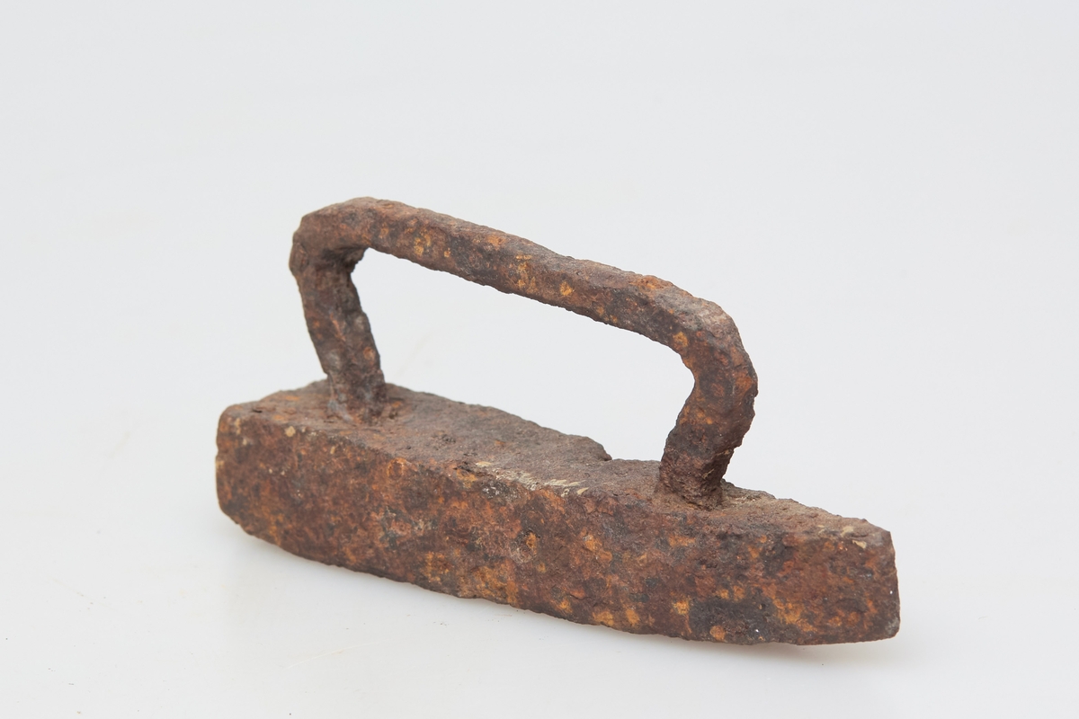 Særdeles lite strykejern med håndtak av jern. Håndsmidd, noe grovt utformet, rustent. Sjelden type, leketøy?