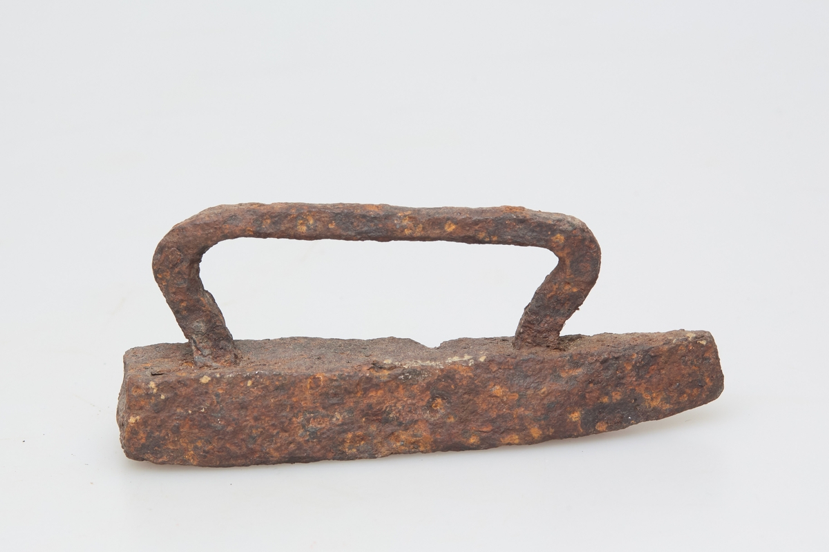 Særdeles lite strykejern med håndtak av jern. Håndsmidd, noe grovt utformet, rustent. Sjelden type, leketøy?