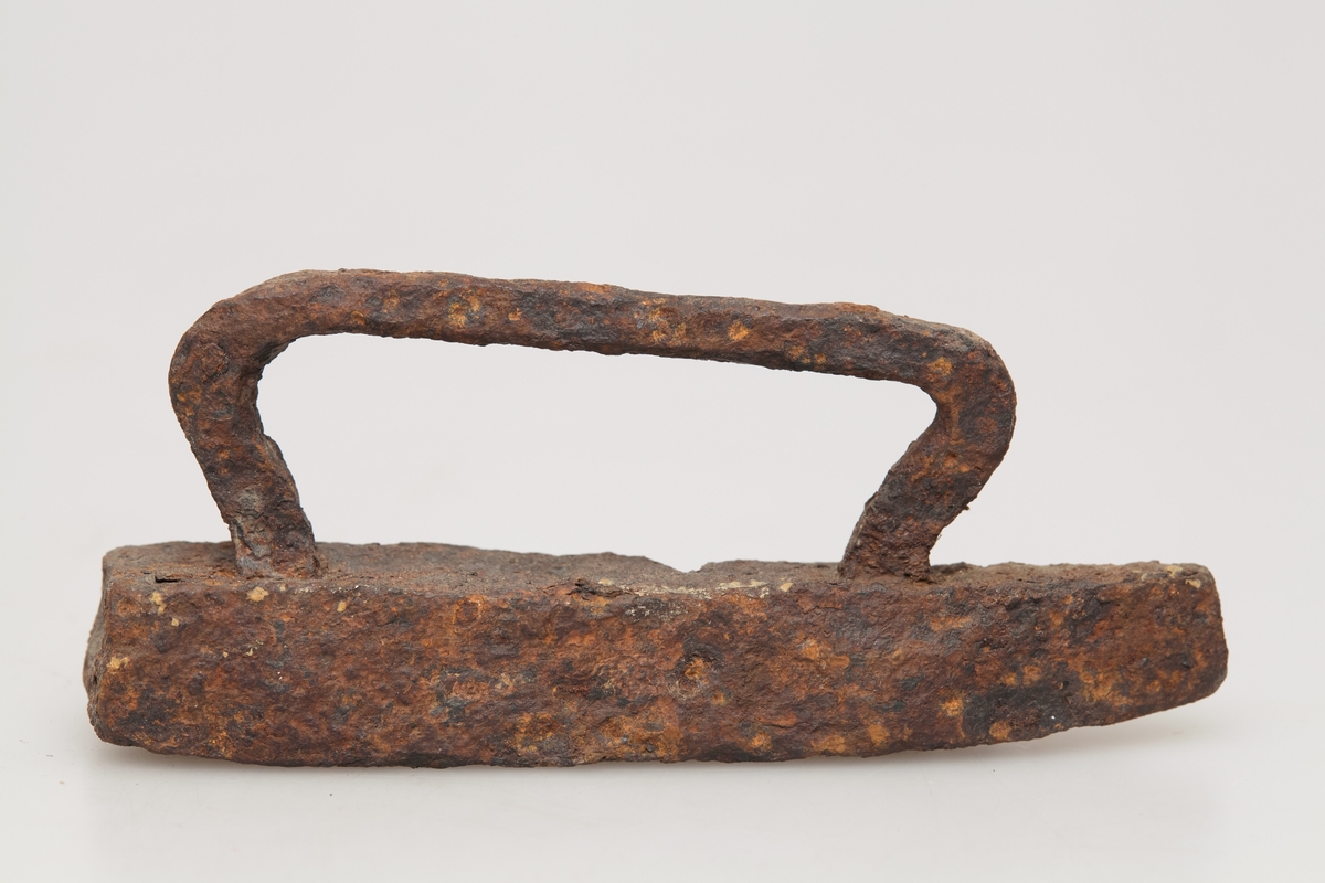Særdeles lite strykejern med håndtak av jern. Håndsmidd, noe grovt utformet, rustent. Sjelden type, leketøy?