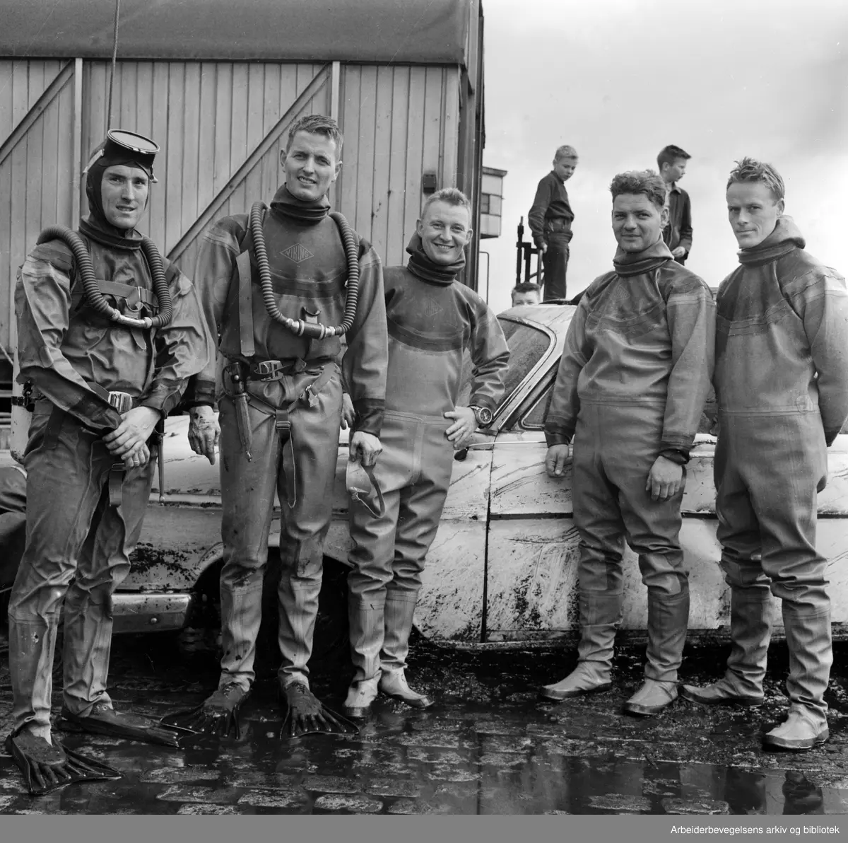 Dykkere fra Oslo Brannvesen heiser i land et bilvrak ved kaia på Vippetangen. August 1962.