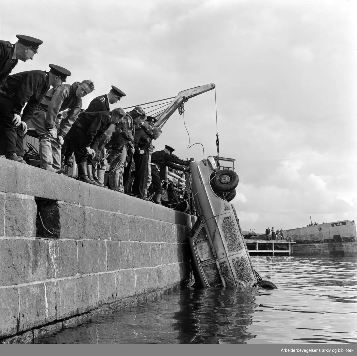 Dykkere fra Oslo Brannvesen heiser i land et bilvrak ved kaia på Vippetangen. August 1962.