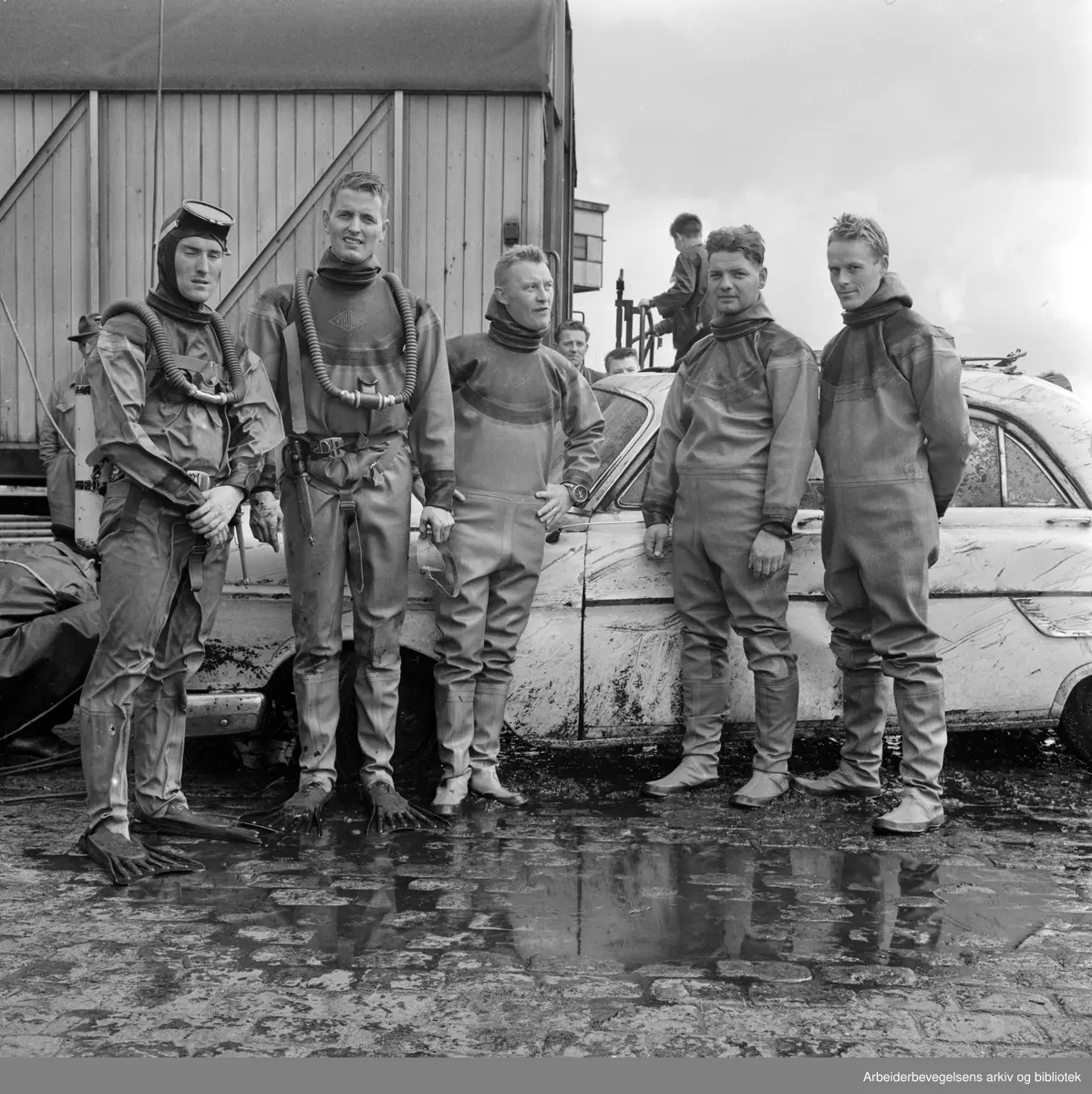 Dykkere fra Oslo Brannvesen heiser i land et bilvrak ved kaia på Vippetangen. August 1962.