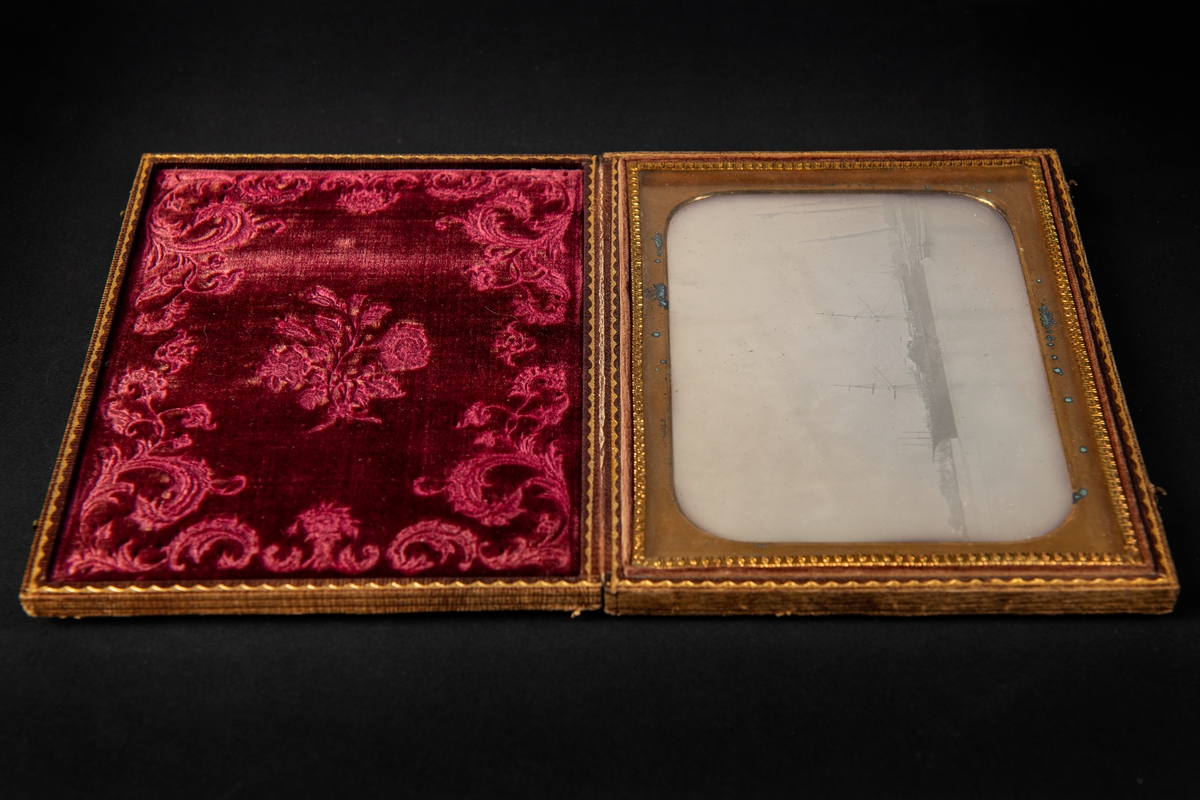Daguerreotypi, föreställande varmluftsskeppet John Ericsson, infattad i ett läderetui med ornamentering. Locket fodrat med mönstrad röd silkessammet.