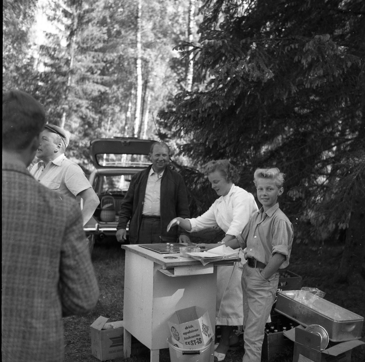 Servering av varmkorv i skogen. En kvinna och en pojke står vid ett mobilt "kök".