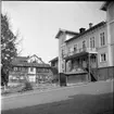 Fotografi mot Hjerströmska gården från Amiralsvägens övre del. Man ser en knuttimrad tvåvåningsbyggnad på tomtens norra sida vars brädfodringen håller på att tas ned i samband med rivning.