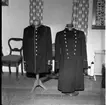 Två uniformsrockar på ställningar.