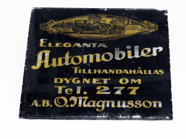 Glasskyltar, 4 st med förgylld text. Bottenfärgen avflagnad på skyltarna.
1) Text: Mjölk ger hälsa, drick därför Säbyholms kontrollerade naturmjölk.
2) Text: Eleganta Automobiler tillhandahålles dygnet om. Tel. 277. A.B. O. Magnusson.
3) Harry Lindberg. Utför alla slags Stenarbeten. Landskrona Kalkbruk, Ständigt lager av kalk.
4) Text: Café Temperance, Frukostar, middagar, supéer.
Inrammad i en svart trätam med krokar upptill för upphängning. Glasskylten har spruckit på två ställen.
