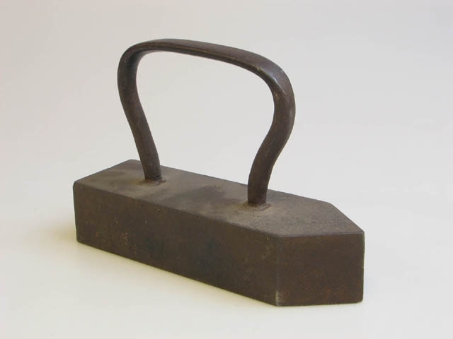 Pressjärn av gjutjärn. Mått: H: 17,5cm, L: 23,5cm, B: 7,2cm.
Strykjärnsfot av plåt (gjord senare); står på små fötter. Mått: H: ca 2cm, L: 27,5cm, B: 15cm.
Man hade i arbetet hela tiden två pressjärn igång. Ett använde man och ett stod på järnspisen under en rund plåthuv med handtag. (Pressjärnet kunde även ställas på gaslågan). Man använde alltid en lapp, när man tog i det heta handtaget.
Har varit utställda i Landskrona museums basutställning "I barnaminne" som stod mellan 1989 och 2007.