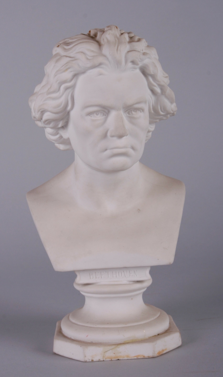 Byste av Beethoven i bisque. Bysten er montert på en rund sokkel, som går over i 8-kantet plate.