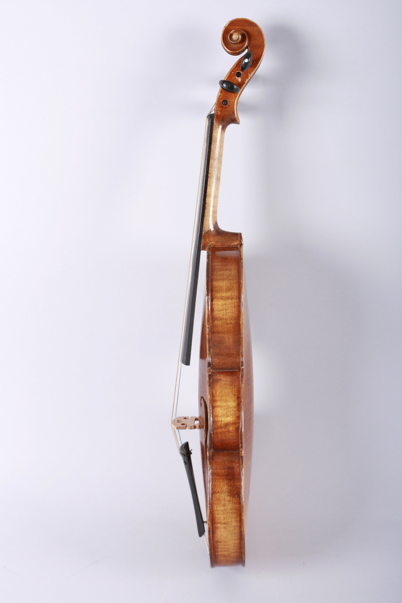 Strengeinstrument i mindre størrelse, 1/4 format(?). Lokk av gran, bunn og sarg ahorn. Lys lakkert. Gripebrett, strengeholder og endeknapp ibenholt. Sortmalte skruer. Mangler hjørneklosser.