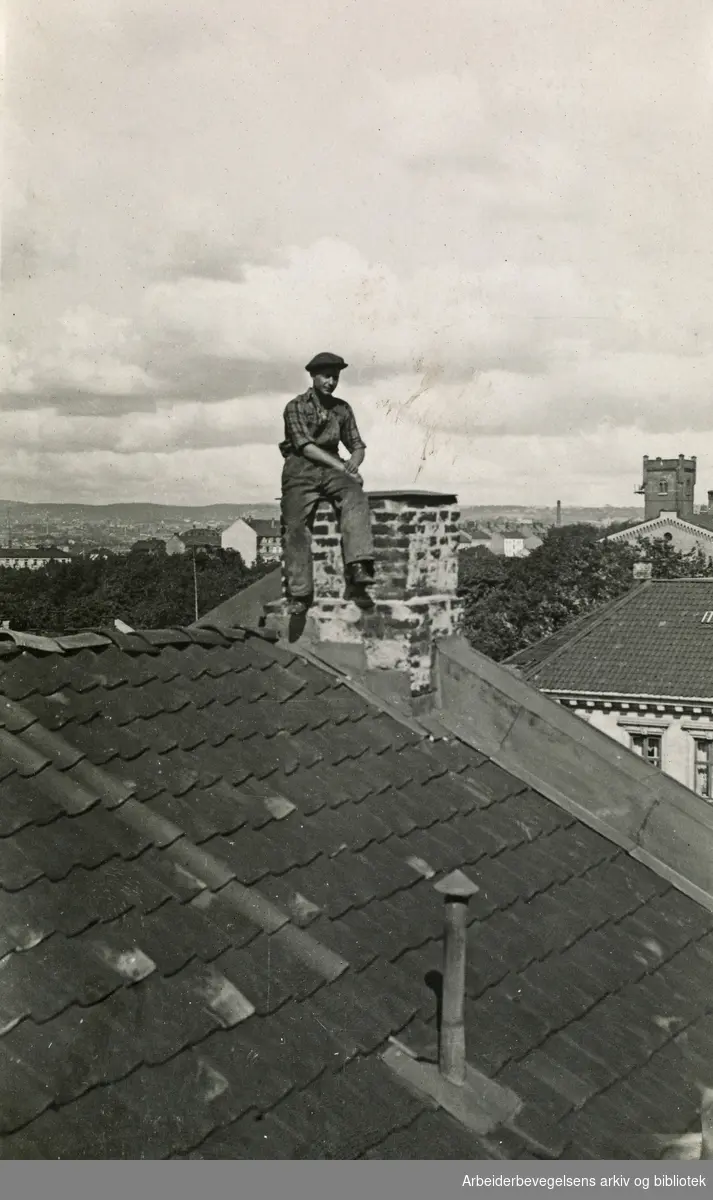 En blikkenslager utfører takarbeide i en bygård på Grønland i Oslo, 1935.