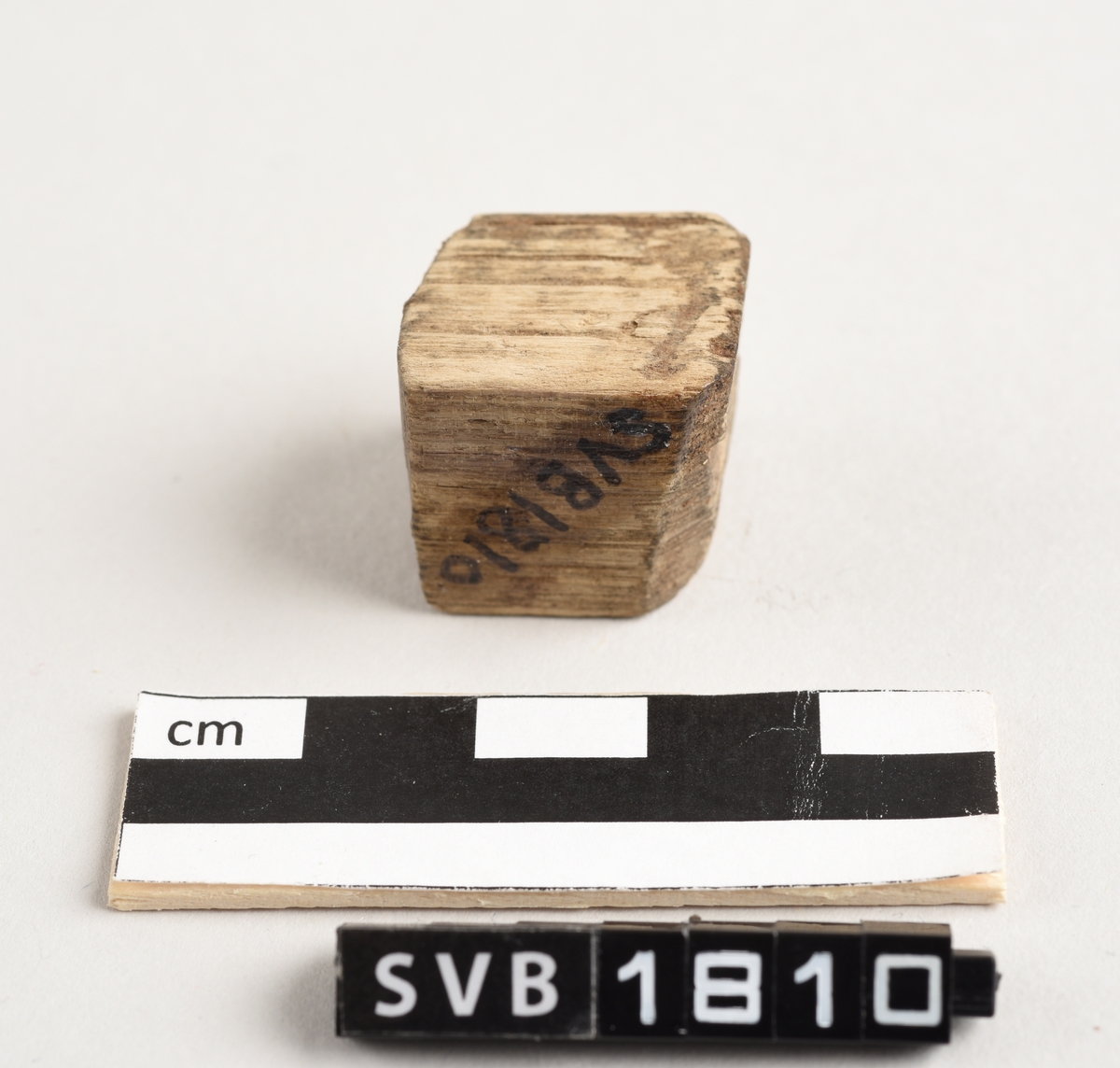 Tregjenstand med en kubisk form. Gjenstanden har en uregelmessig overflate og overflaten er ubehandlet.