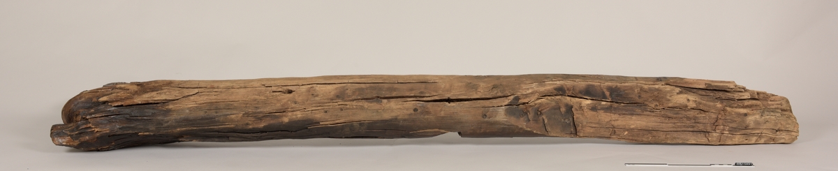 Stevn av båt av treverk, med fem hull for jernbolter. To jernbolter bevart.  Merket med tusj som "III-23".
