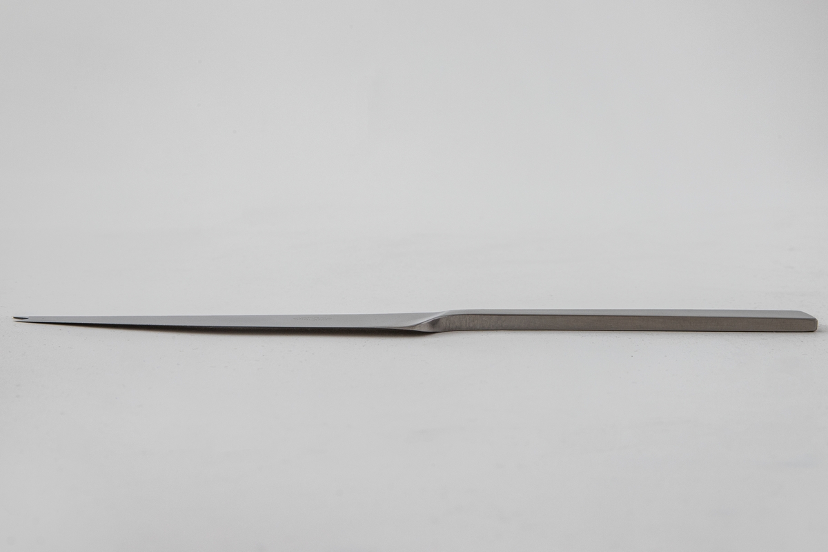 Ostekniv i polert, rustfritt stål. Blad med svakt kurvet rygg, som ender i en gaffelformet avsluttning. Det rettlinjede skaftet er mattert, mens bladet er polert, slik at det oppstår en kontrast mellom de blanke og matte partiene.