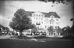 Vid Hovrättstorget i Jönköping står människor och väntar på spårvagnen från Rosenlund. I det gigantiska Grand Hotel som invigdes år 1904, finns förutom hotell även restaurang och teater.