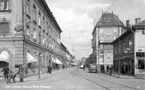 Östra Storgatan i Jönköping, fotograferad från Vindbron. Till vänster Stora hotellets byggnad med Handelsbankens lokal på hörnet och med reklam för Pratts bensinstation och Karnells tobaksaffär. Det höga huset till höger var Smålands enskilda bank och i trähuset låg Lilla hotellet.