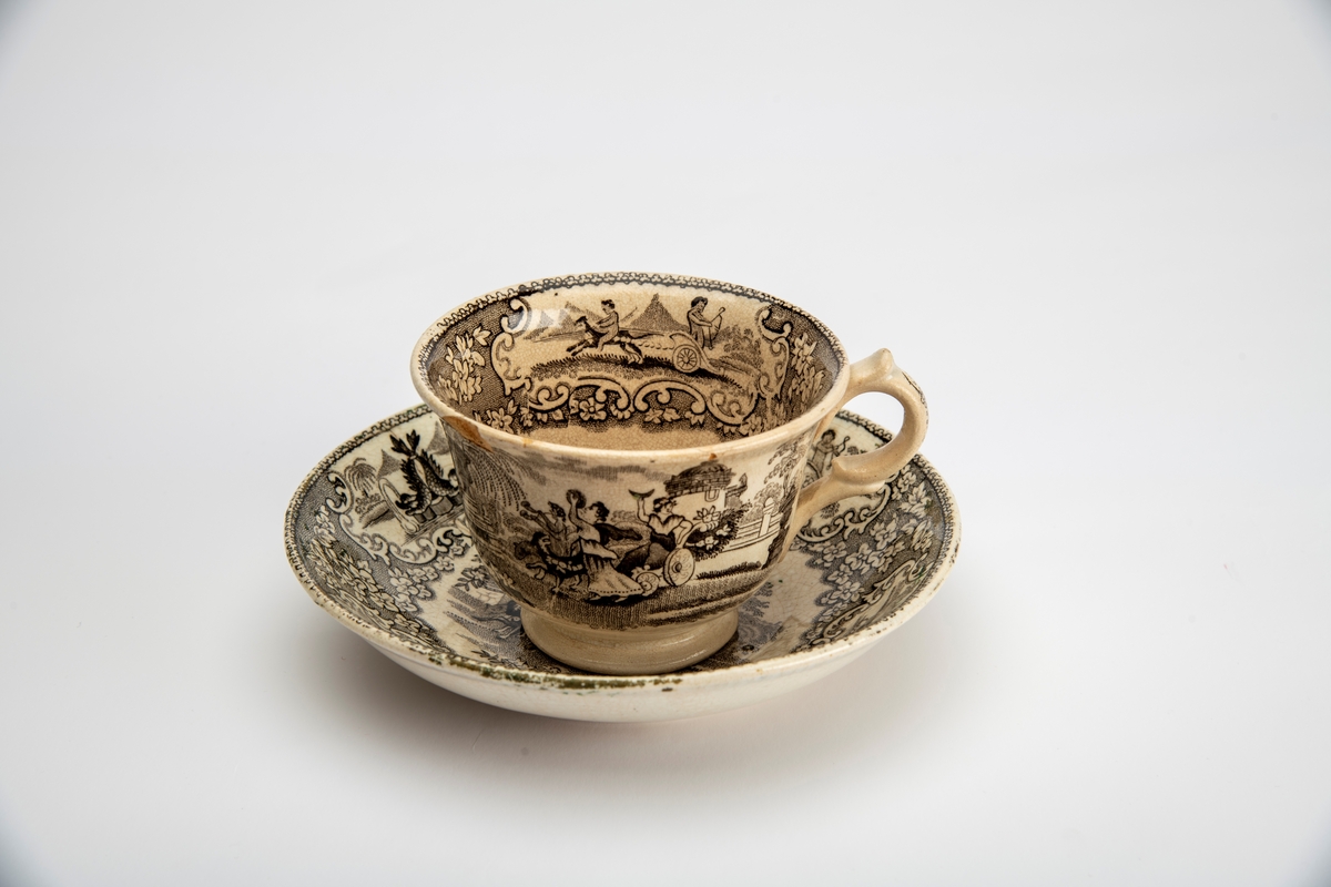 A: Kopp. Sidene utsvunget mot munningen, innsvunget mot fotring, buet,  fliket hank. Trykt dekor i brunsort:  Opptog som kjører gjennom en park, gjentatt på begge sider av koppen,:  innv. meget bred bord m. blomster, samt felt med bueskytter i 2-hjuls stridsvogn, trukket av hund med rytter. Et annet felt med springvann, dannet avto delfiner, pseudorokokko innramming, i bunnen parklandskap med urne og busk, samt svaner som seiler i en damm.  

B: Skål. Lite, flatt speil, buede sider; sidene dekket av blomsterbord m. fire felter: To med delfinspringvann  To med bueskytter i stridsvogn; i speilet det kvinnelige opptog i parken.  Stemplet under bunnen: " Triumphal Car"  under due med utspilte vinger og glorie, dessuten:  J Jamieson & Co.