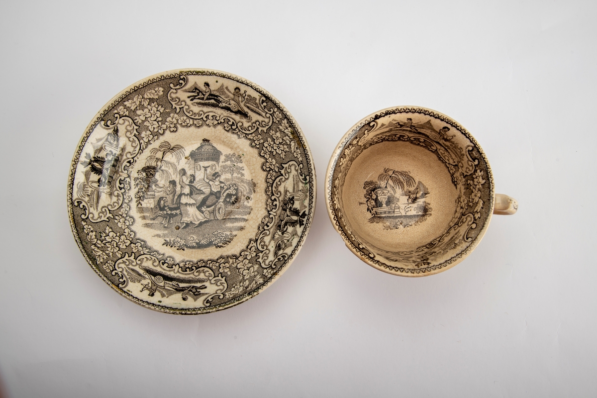 A: Kopp. Sidene utsvunget mot munningen, innsvunget mot fotring, buet,  fliket hank. Trykt dekor i brunsort:  Opptog som kjører gjennom en park, gjentatt på begge sider av koppen,:  innv. meget bred bord m. blomster, samt felt med bueskytter i 2-hjuls stridsvogn, trukket av hund med rytter. Et annet felt med springvann, dannet avto delfiner, pseudorokokko innramming, i bunnen parklandskap med urne og busk, samt svaner som seiler i en damm.  

B: Skål. Lite, flatt speil, buede sider; sidene dekket av blomsterbord m. fire felter: To med delfinspringvann  To med bueskytter i stridsvogn; i speilet det kvinnelige opptog i parken.  Stemplet under bunnen: " Triumphal Car"  under due med utspilte vinger og glorie, dessuten:  J Jamieson & Co.