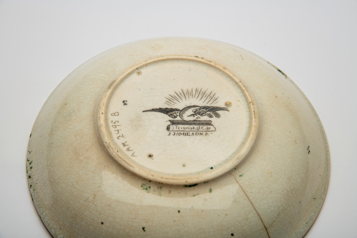A: Kopp. Sidene utsvunget mot munningen, innsvunget mot fotring, buet,  fliket hank. Trykt dekor i brunsort:  Opptog som kjører gjennom en park, gjentatt på begge sider av koppen,:  innv. meget bred bord m. blomster, samt felt med bueskytter i 2-hjuls stridsvogn, trukket av hund med rytter. Et annet felt med springvann, dannet avto delfiner, pseudorokokko innramming, i bunnen parklandskap med urne og busk, samt svaner som seiler i en damm.  

B: Skål. Lite, flatt speil, buede sider; sidene dekket av blomsterbord m. fire felter: To med delfinspringvann  To med bueskytter i stridsvogn; i speilet det kvinnelige opptog i parken.  Stemplet under bunnen: " Triumphal Car"  under due med utspilte vinger og glorie, dessuten:  J Jamieson & Co.