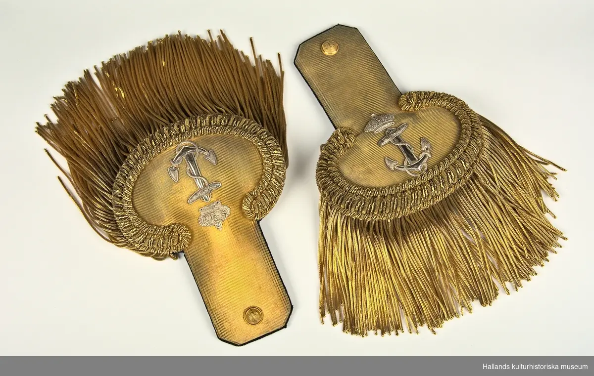 A:1-2: Epåletter för personal av officerrang inom flottan. Undersidan på epåletterna är klädda med en matta av mörkblå samet och översidan med ett band av guldgalon. På epåletthalsen sitter en liten knapp med flottans vapen och på klaffen finns flottans vapen broderad i silvertråd. Epåletterna är även försedda med fransar i tunn guldsnodd.

På undersidan finns en hake (för infästning på vapenrock) av guldmetall med stämpeln: "F&Co".

B: Förvaringsask av papp målad i en mörkgrön nyans.