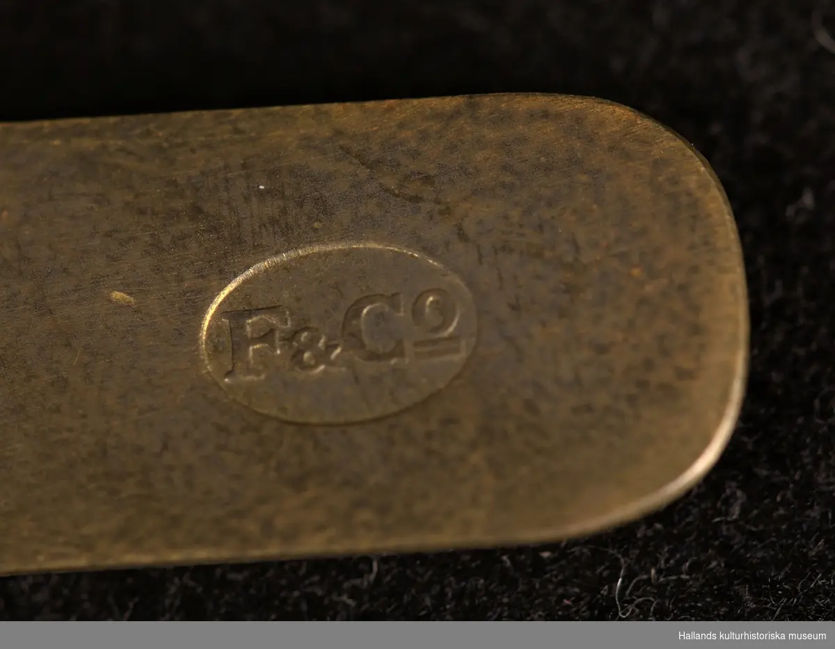 A:1-2: Epåletter för personal av officerrang inom flottan. Undersidan på epåletterna är klädda med en matta av mörkblå samet och översidan med ett band av guldgalon. På epåletthalsen sitter en liten knapp med flottans vapen och på klaffen finns flottans vapen broderad i silvertråd. Epåletterna är även försedda med fransar i tunn guldsnodd.

På undersidan finns en hake (för infästning på vapenrock) av guldmetall med stämpeln: "F&Co".

B: Förvaringsask av papp målad i en mörkgrön nyans.