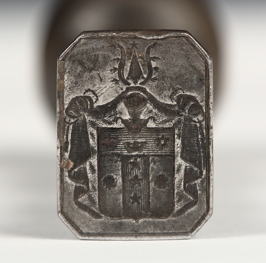 Sigillstamp av järn med svarvat brunbetsat träskaft. Längst ner på skaftet sitter en mässingring. Stämpeln utgör det Erhenpolska släktvapnet.