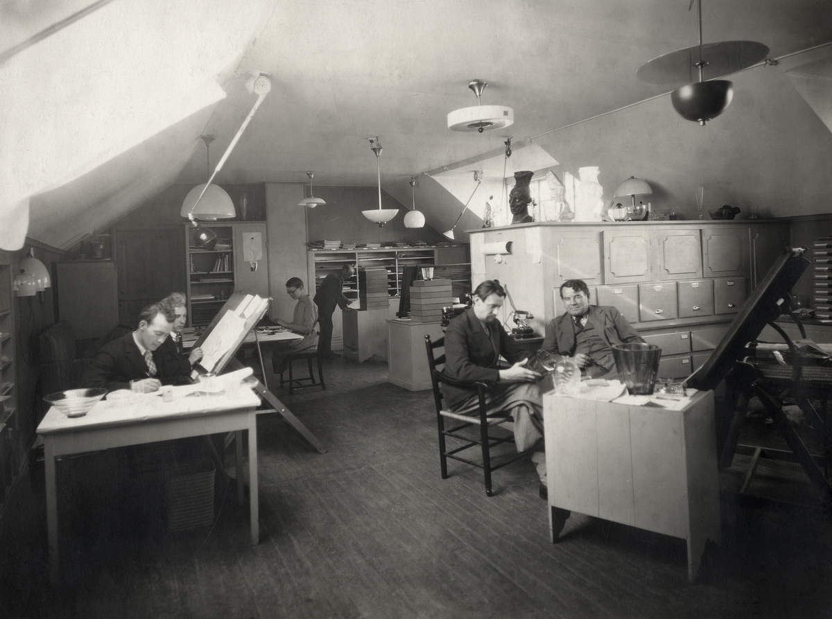 Orrefors glasbruk.
Interiör från ritkontoret. Fr. vänster syns: John Selbing, Nils Landberg, Florence (Flory) Gate, okänd, Vicke Lindstrand och Simon Gate.