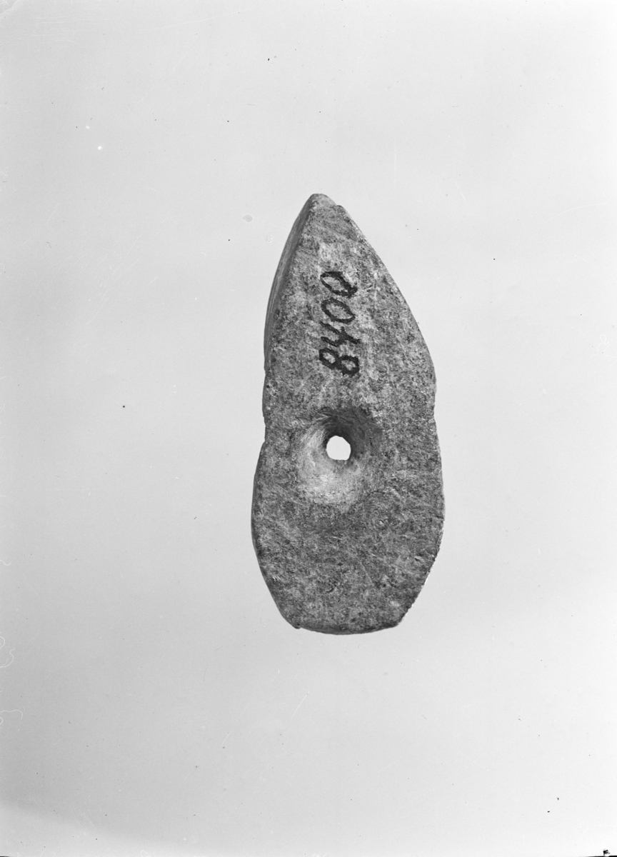 Opprinnelig katalogtekst: Liten tarvelig skåret miniatyrøks med hull av kleberstein, rimeligvis tatt ut av veggen på et kleberkar. Stykkets lengde er 6,1 cm, største bredde 2,6 cm. Hullet er skåret inn fra begge sider. På undersiden er fordypningen for hull forlenget til den ene side. (fig. 6a-b). 
Ny beskrivelse etter revisjon: "Miniatyrøks" av kleber med bikonisk "skafthull" i midten, av form nærmest som en liten skafthulløks eller båtøks, men konkav på oversiden og med en langsgående renne fra "skafthull" til "egg". Brukt som nålebryne? 