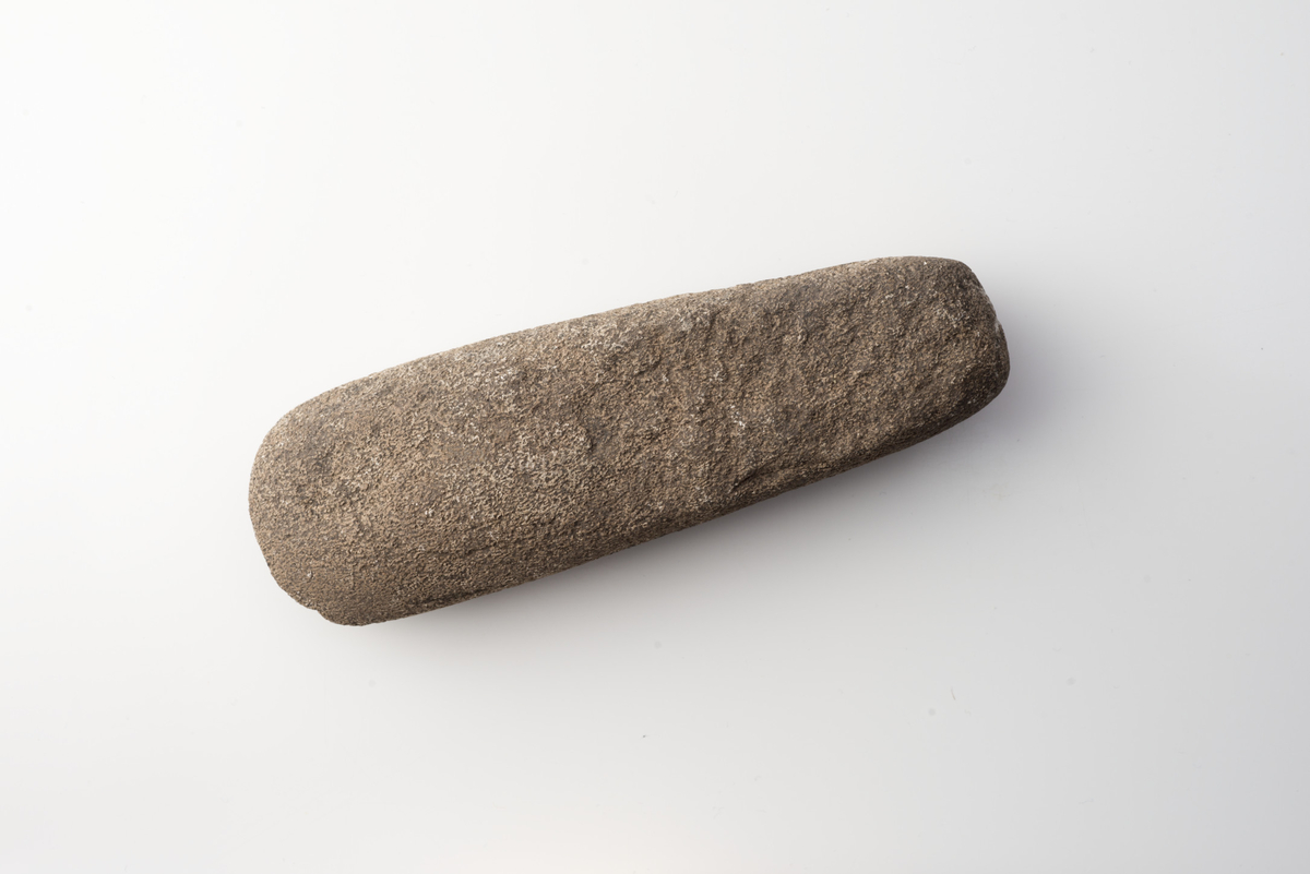 "3224. Butnakket øks af diabas nærmest lignende R. 11. Overfladen især paa den ene side er adskillig forvitret. Øksen er 14,6 cm lang, 4,4 cm bred over den afrundede eg og 2,8 cm bred over banen. Tykkelsen er omtrent jævn 2,6 cm."   Tykknakket, tykkbladet øks av bergart, Malmers var. 2, i samsvar med beskrivelsen. Stl: 145 mm, stbr: 46 mm, stt: 27 mm. Nakke br: 35 mm, nakke t: 26 mm.
