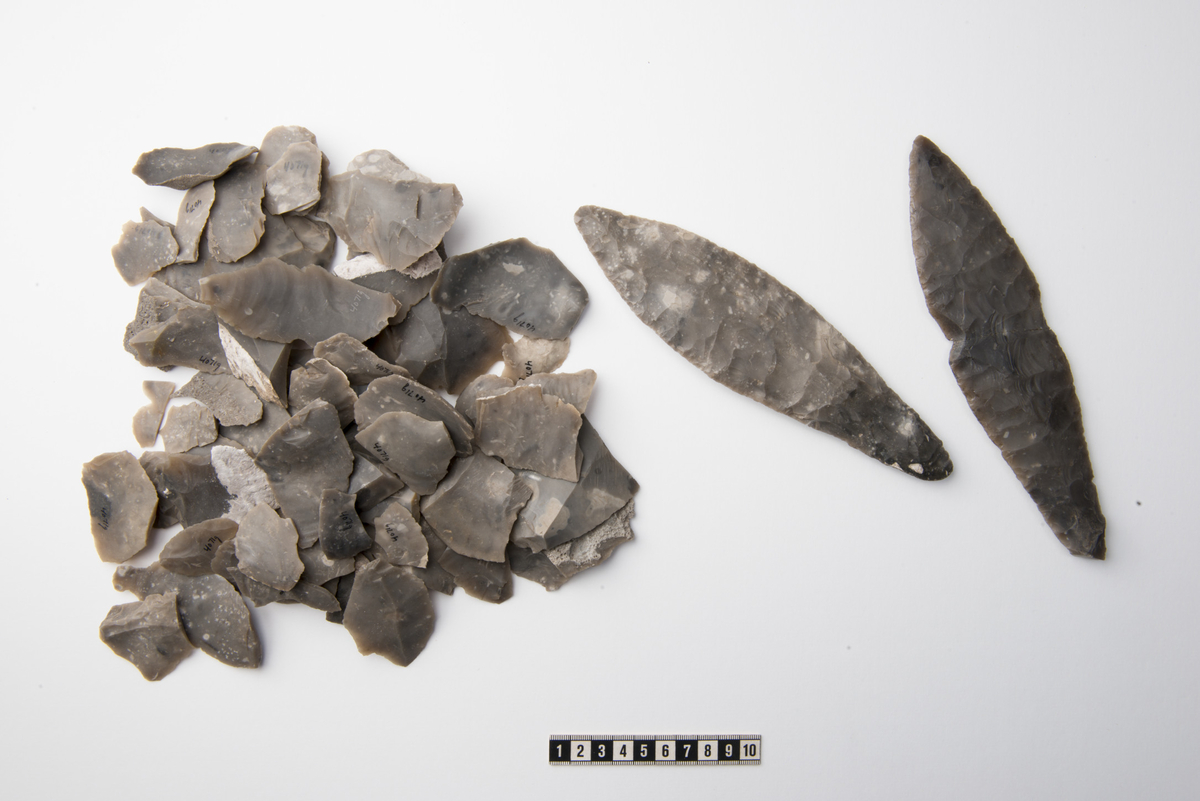 "4071 g. 120 flintfliser, større og mindre. De fleste er uregelmæssige flekker, enkelte med slagbuler, men ingen viser tegn til bearbeidelse. De er alle av lys, graa flint."
Etthundreogtjue avslag av grå og gråbrun flint (flere forskjellige knoller), stl: 11-81 mm. De fleste har retusj/bruksretusj.